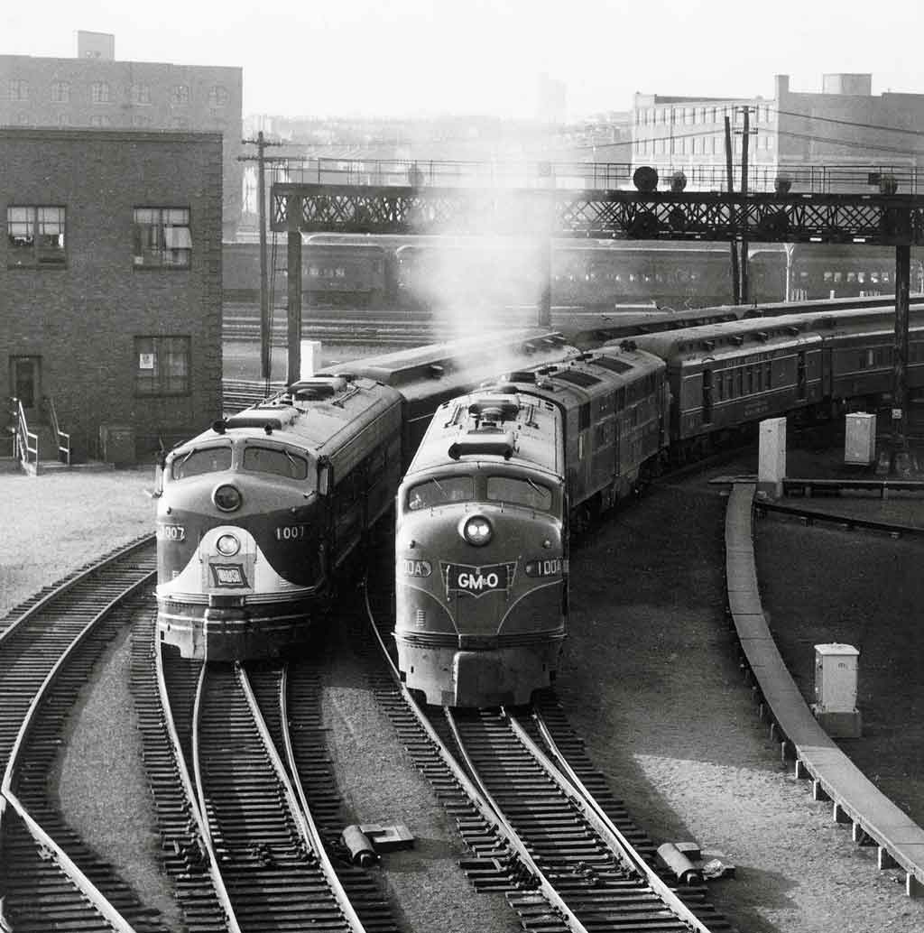 A black and white photo of two locomotives turning a corner at the same time