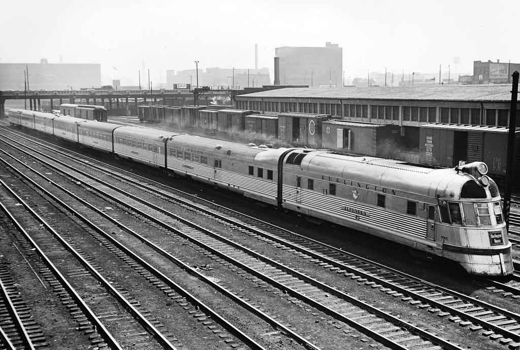 A black and white photo of a train sitting outside a station