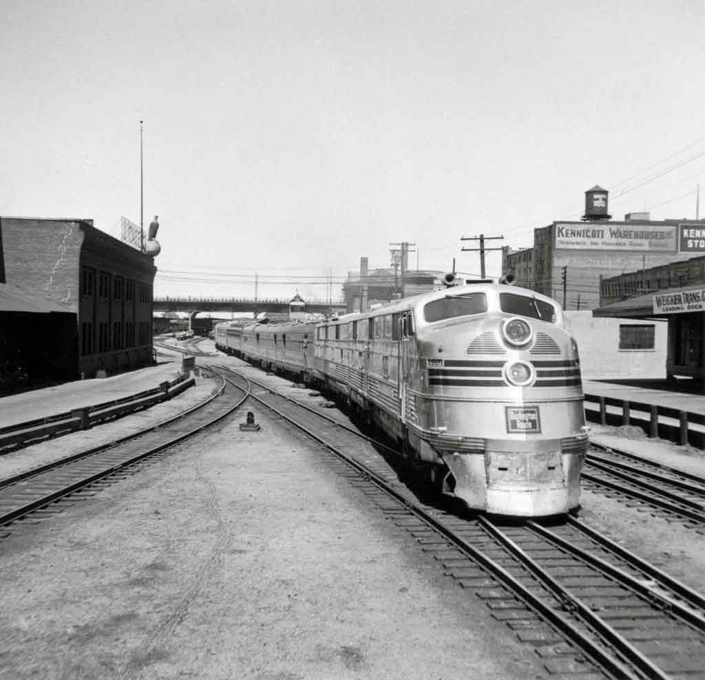 A black and white close up photo of a train traveling through a station