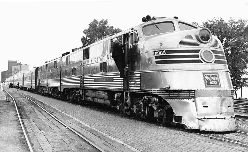 A black and white photo of a conductor climbing up a ladder into the train