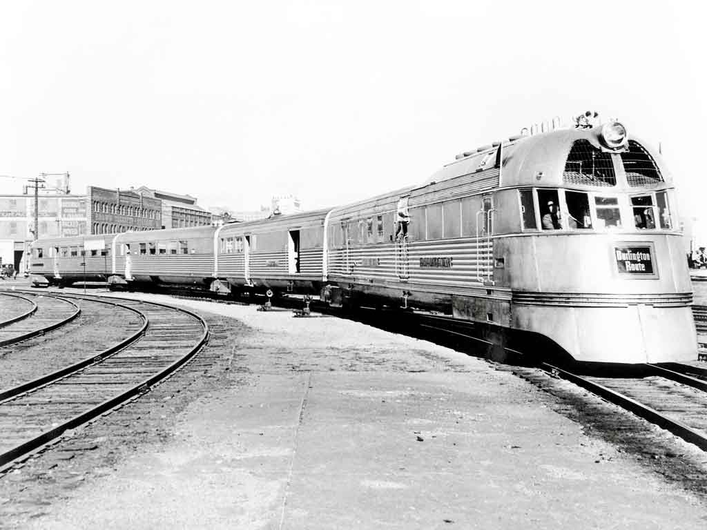 A black and white train with people on it turning a corner