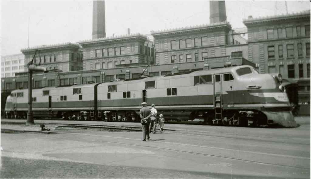 A black and white photo of a couple people standing outside a locomotive