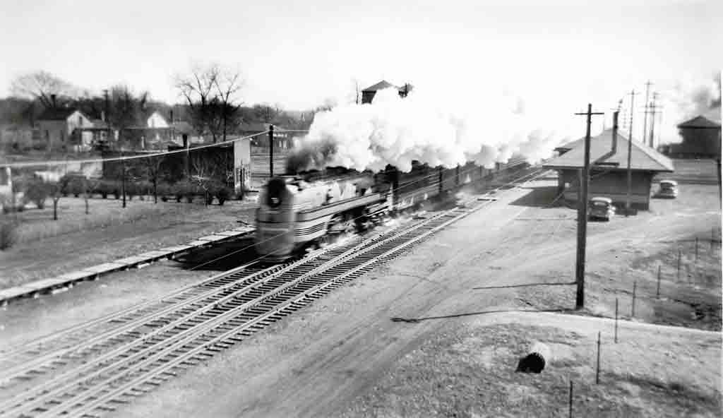 A black and white photo of a train with big white smoke coming out of its chimney