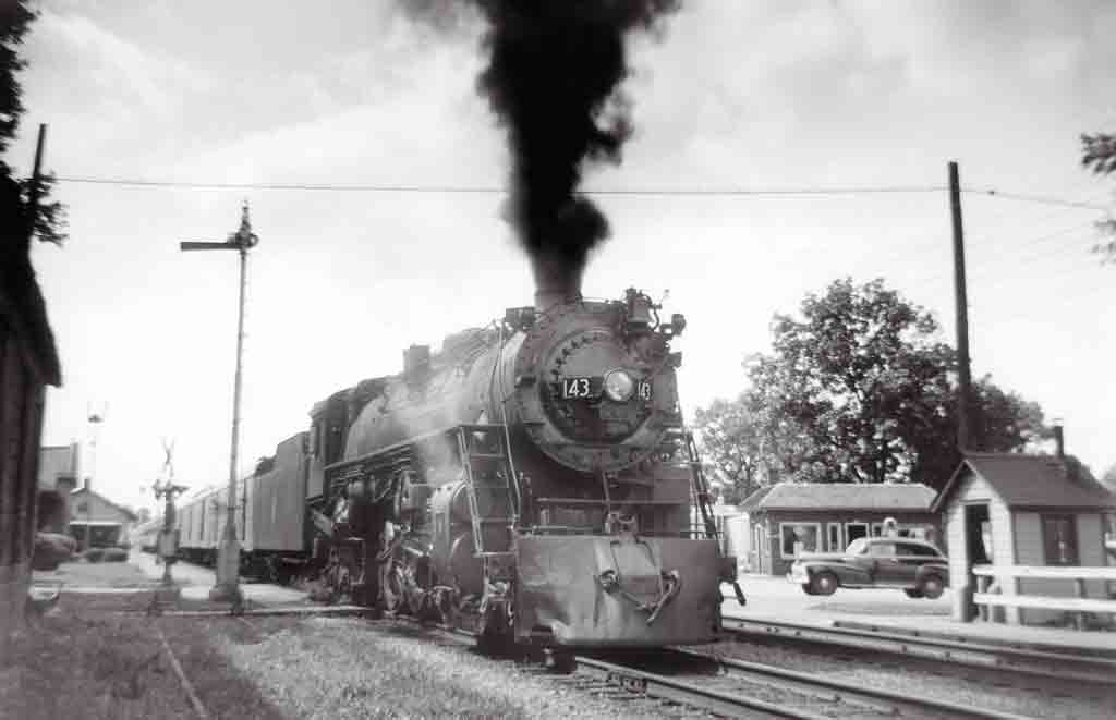 A black and white photo of a locomotive with black smoke coming out of its chimney