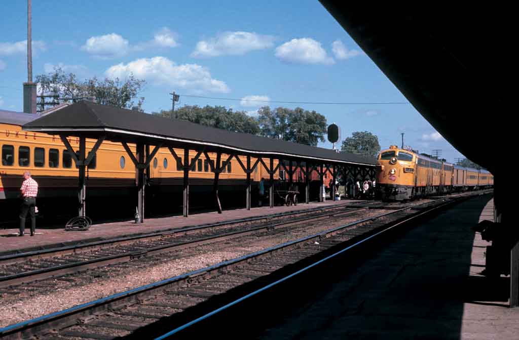 An orange train turning into a train station