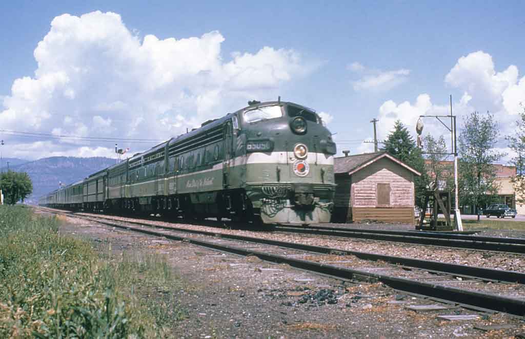 A green and white locomotive on the tracks