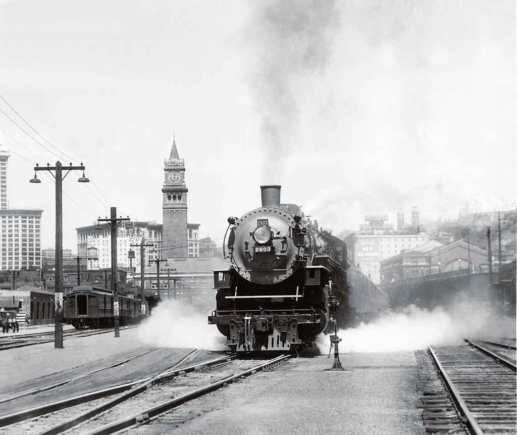 A back and white photo of a train leaving a station