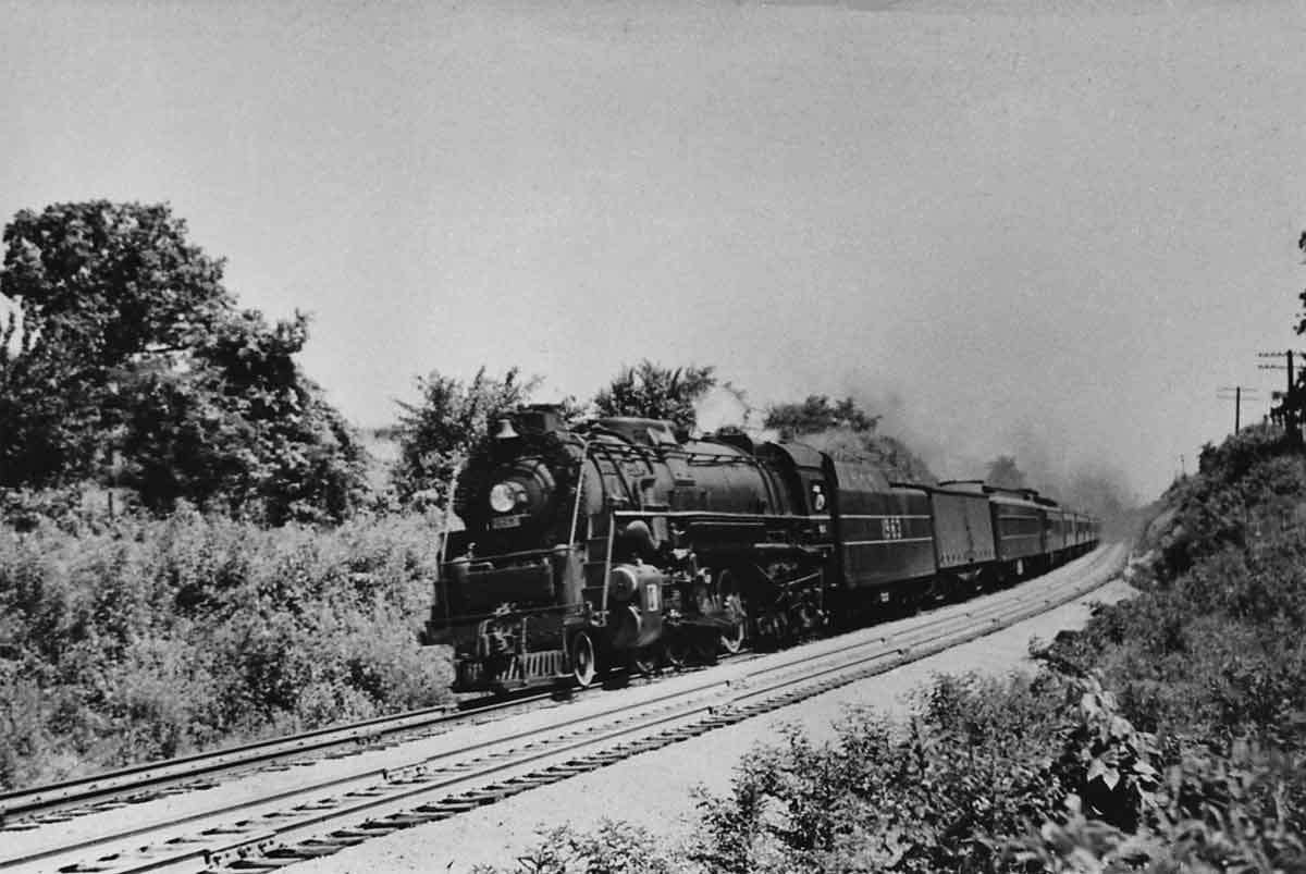 A black and white photo of a train turning a corner