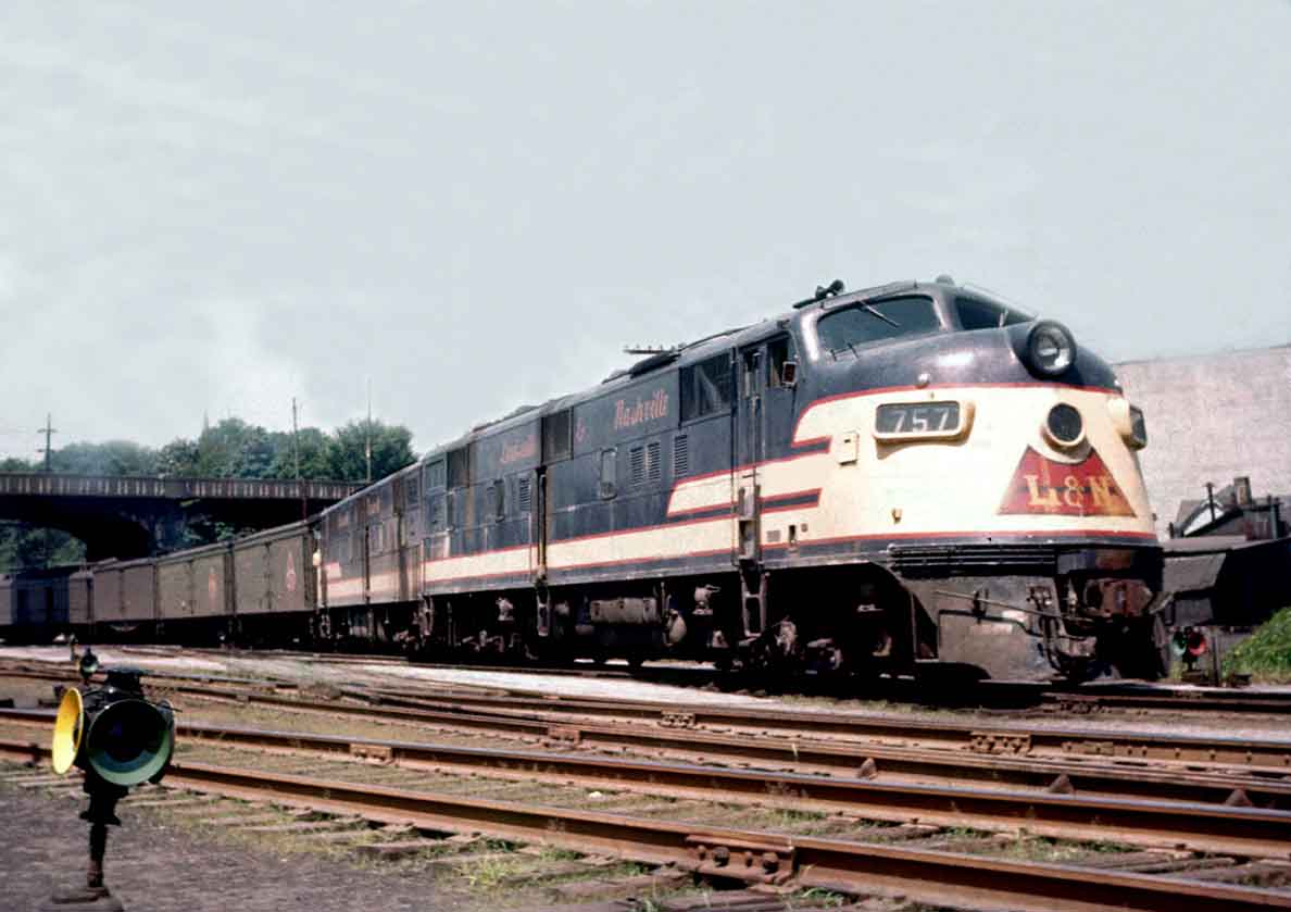 A black, yellow, and red train parked under a bridge