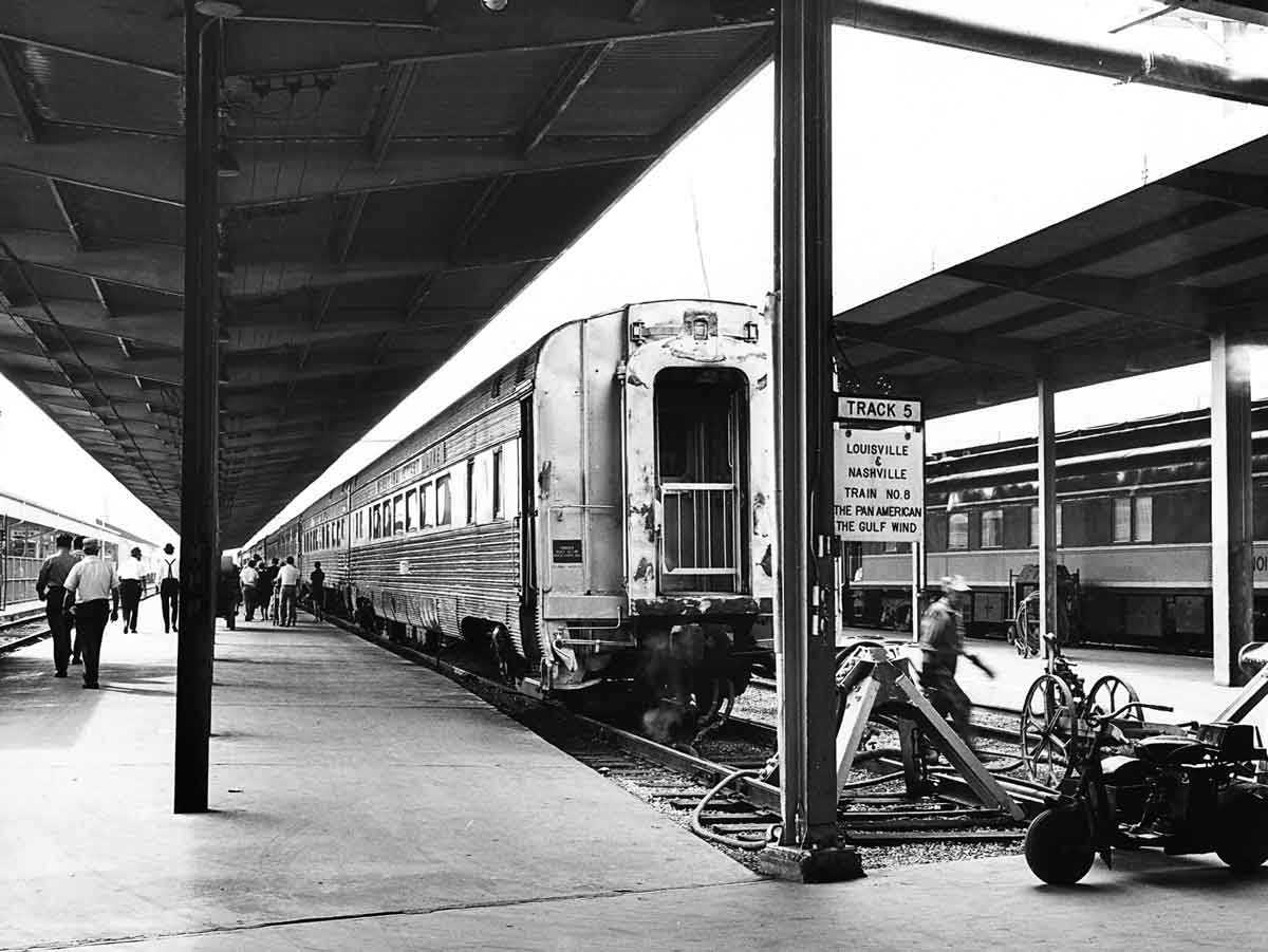 A black and white photo of people walking through a train station