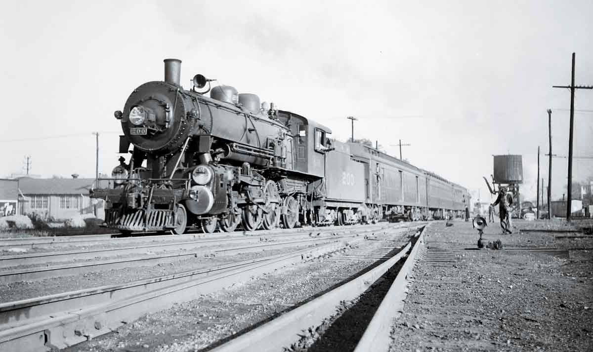 A black and white photo of a train passing by someone standing outside