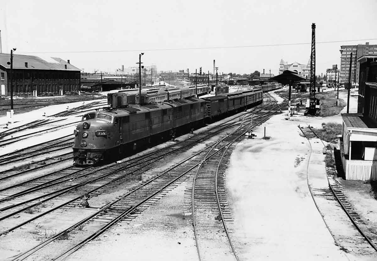 A black and white photo of a train departing a station