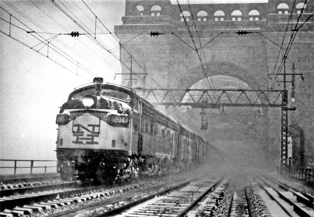 a diesel passenger train crossing a bridge on a snowy day
