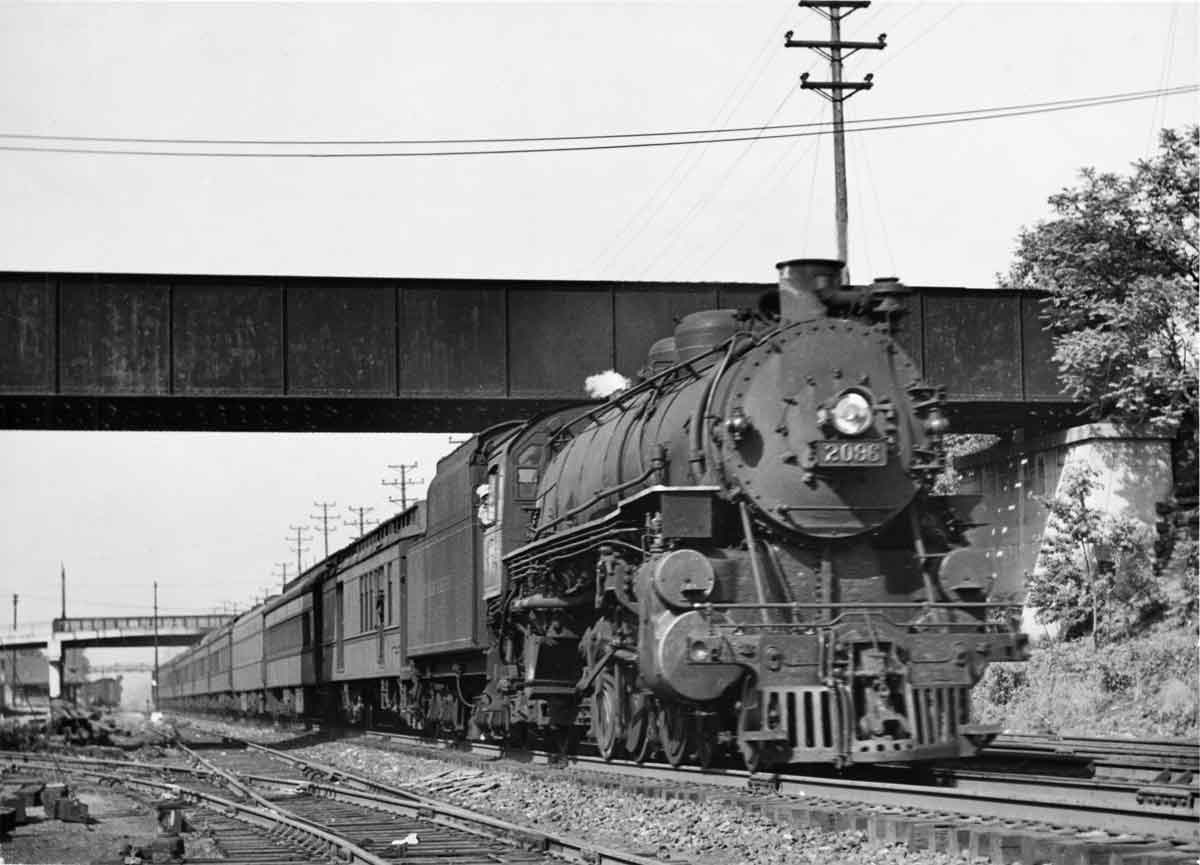 A black and white photo of a training moving under a bridge