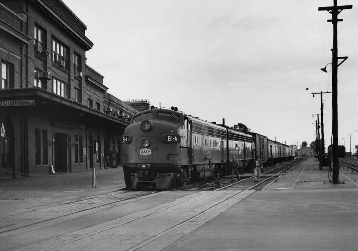a diesel pulling passenger cars through a town