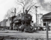 a steam engine passenger train sitting next to a train station