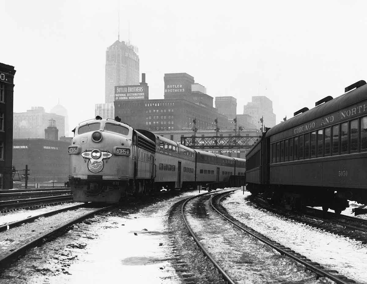 a passenger train passes another passenger train with Chicago buildings in the background