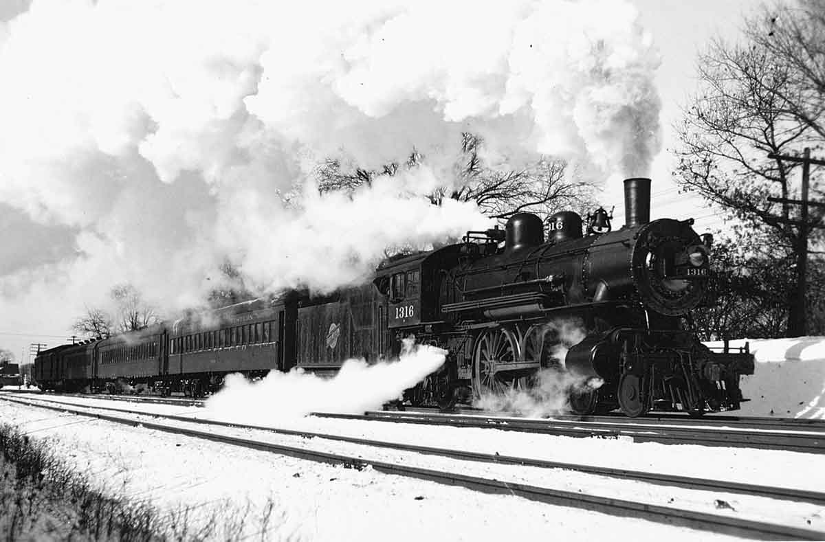 a steam engine pulling passenger cars on a winter day