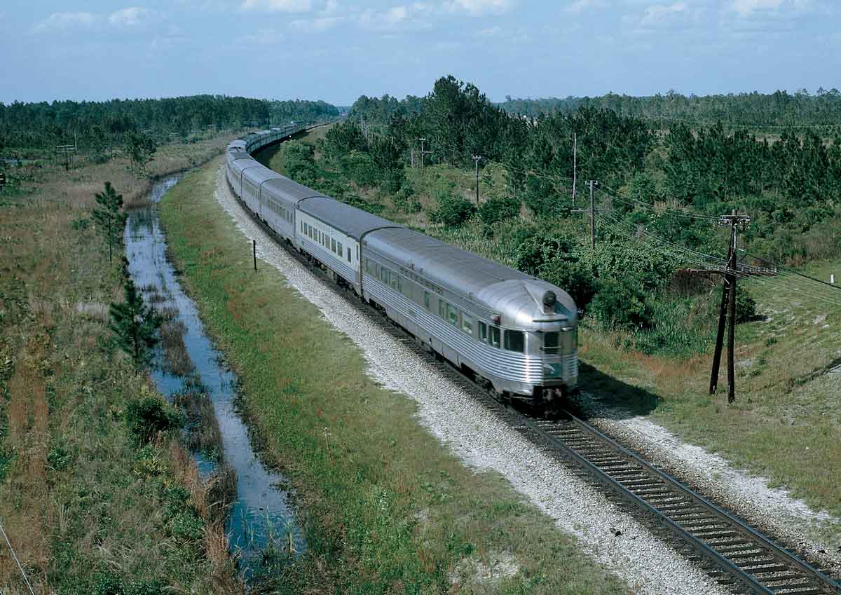 A streamlined silver-colored passenger train as seen above and from the rear.