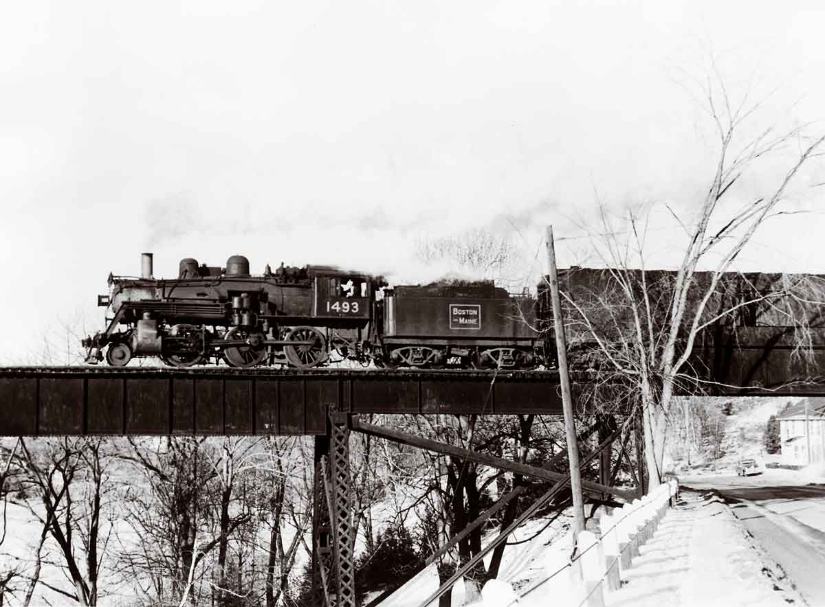 A black and white photo of a train crossing a bridge