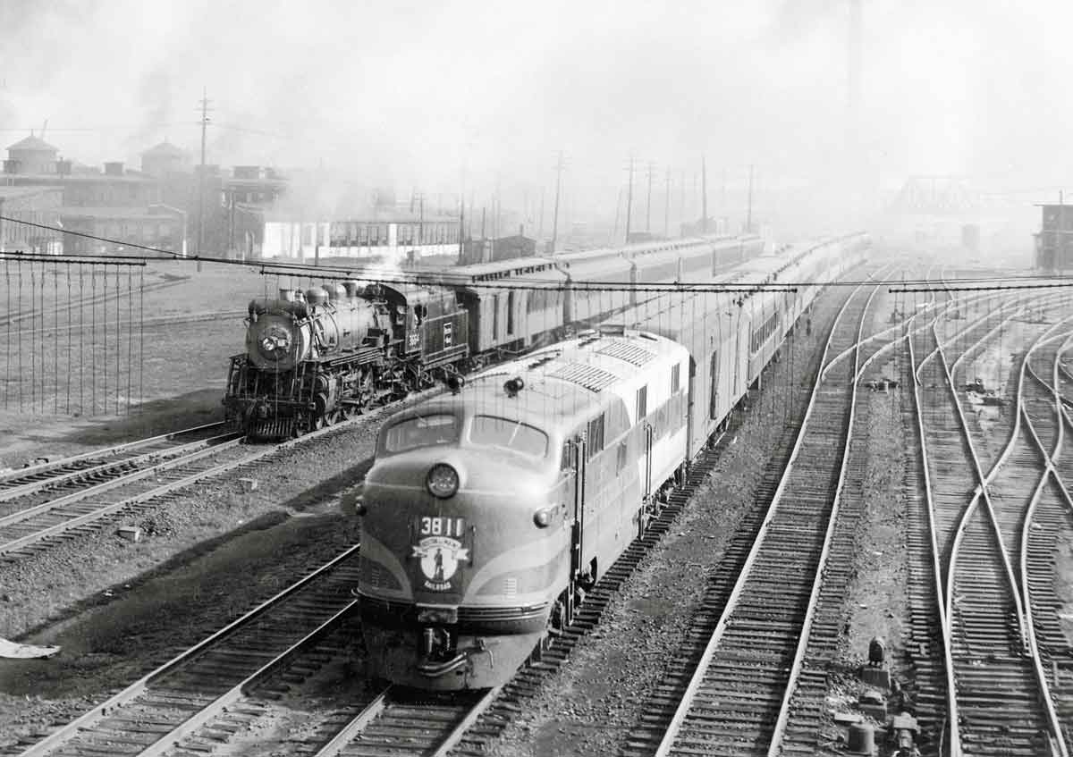 A black and white photo of two trains coming down the tracks