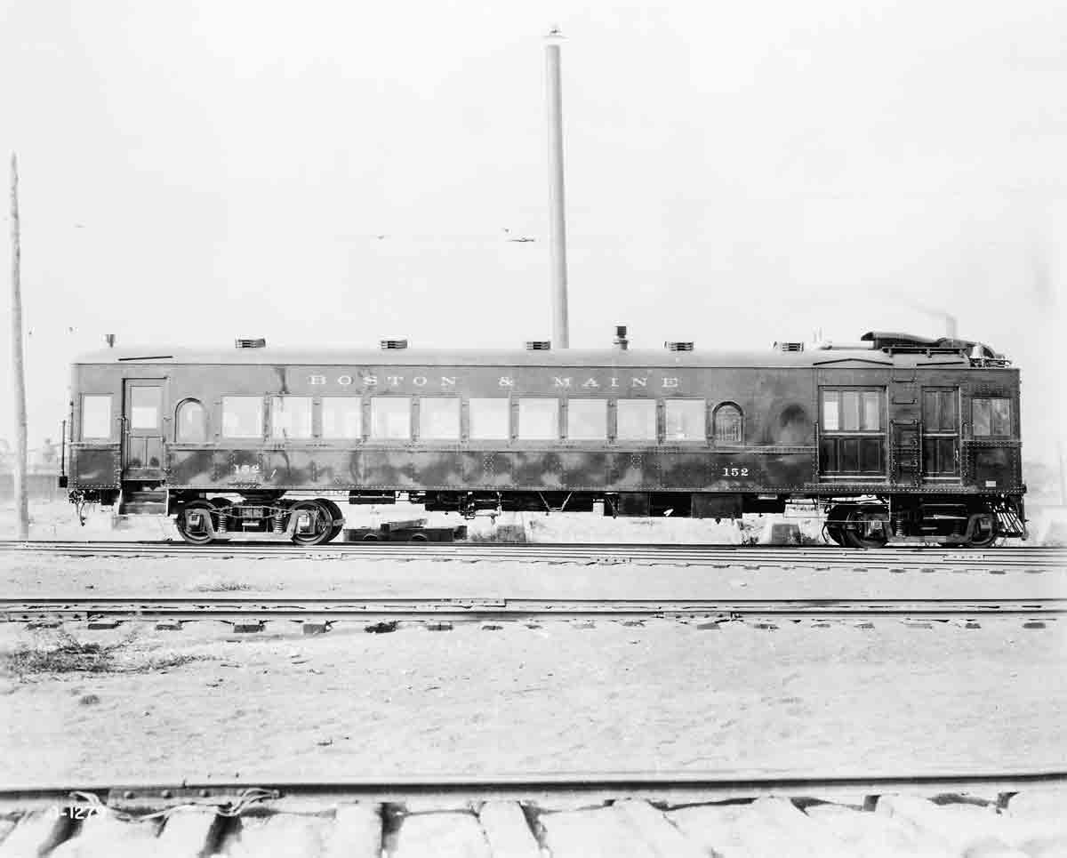 A black and white photo of a gas-electric car sitting on the tracks