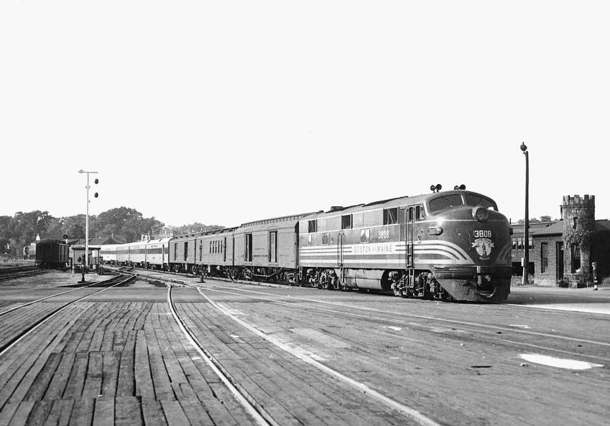 A black and white photo of a locomotive approaching a station