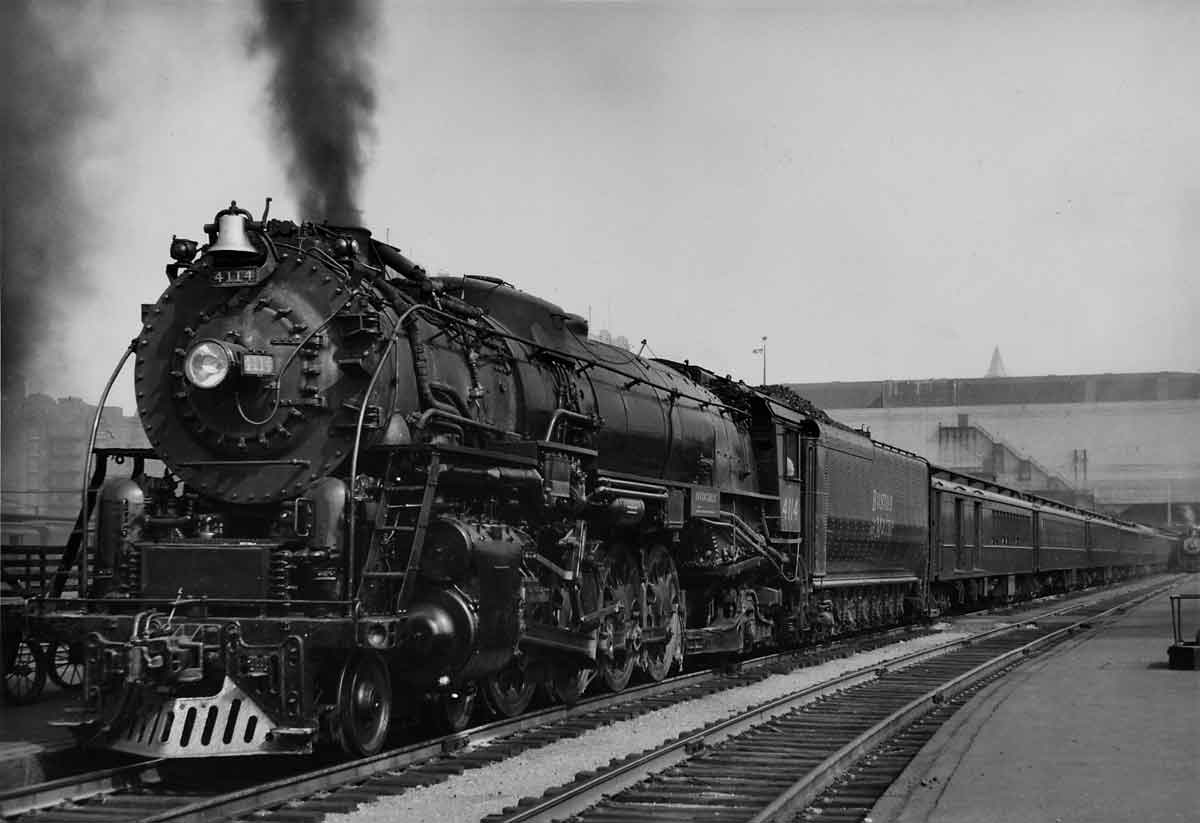 A close up black and white photo of a train with black smoke coming out of its chimney