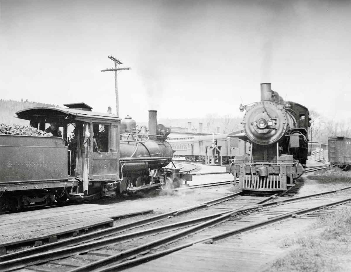 A black and white photo of two trains passing each other on the tracks