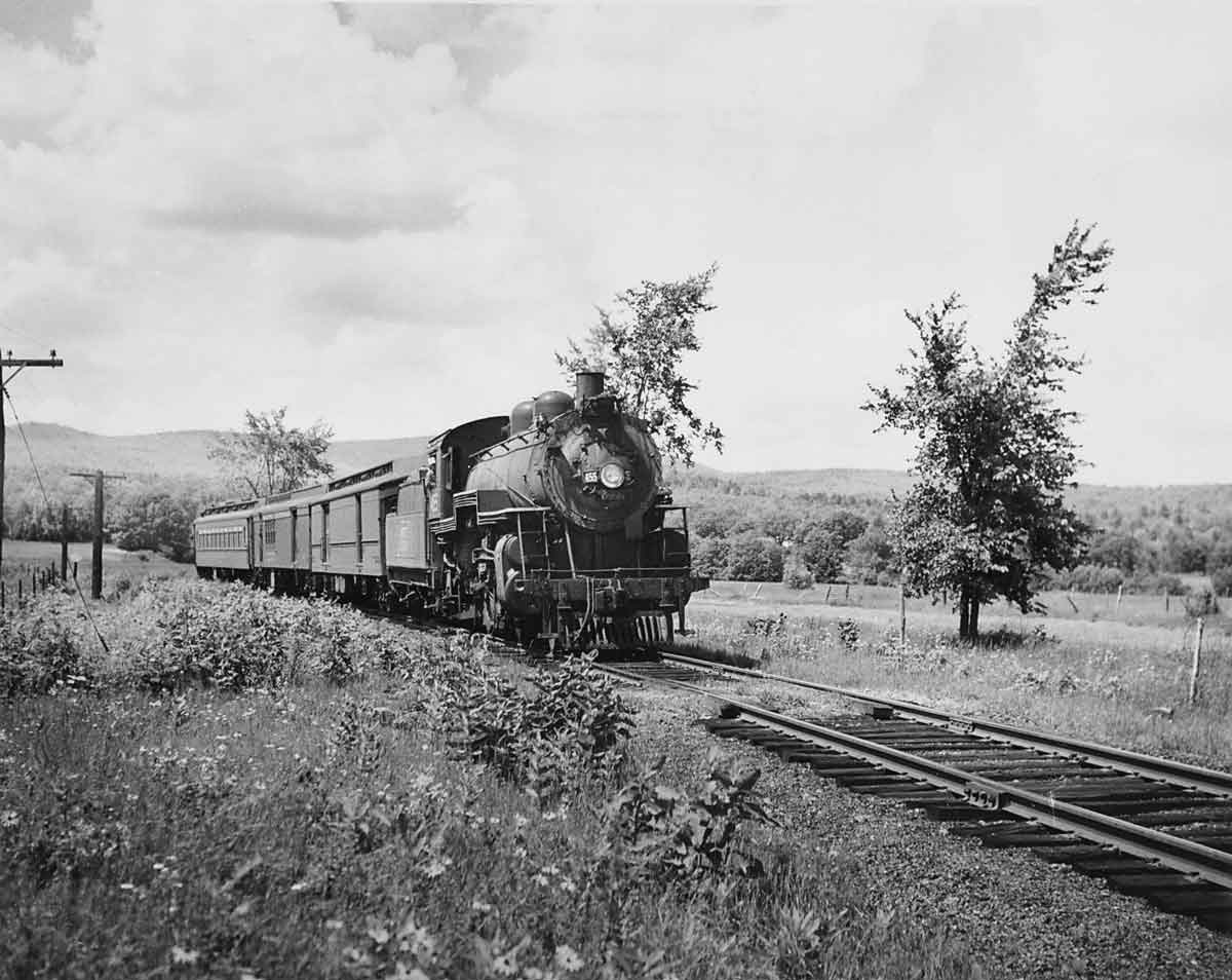 A black and white photo of a locomotive moving on the tracks