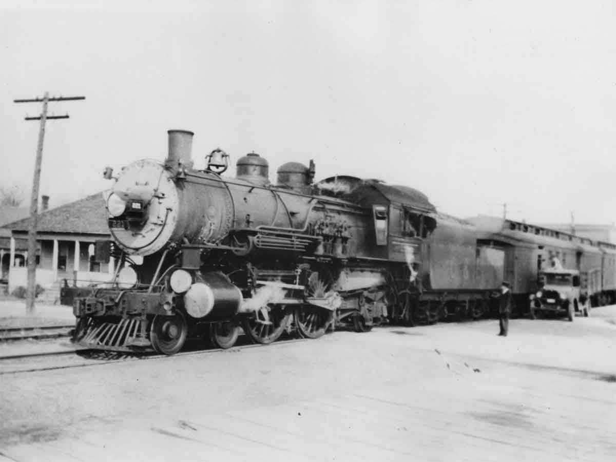 a steam engine and passenger cars at a station