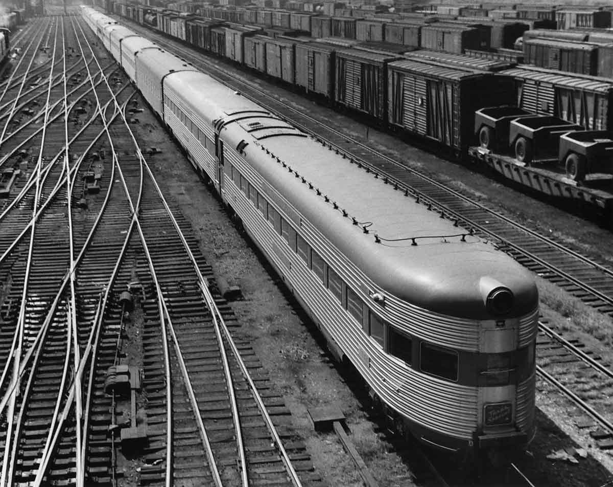 a train yard with a passenger train with the focus of the photo being the observation car