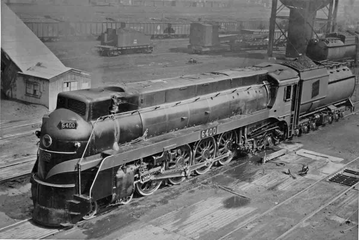 a streamlined steam engine in a rail yard