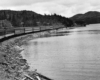 a passenger train on a curve around a body of water