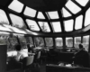 people sitting in an observation car with multiple windows 
