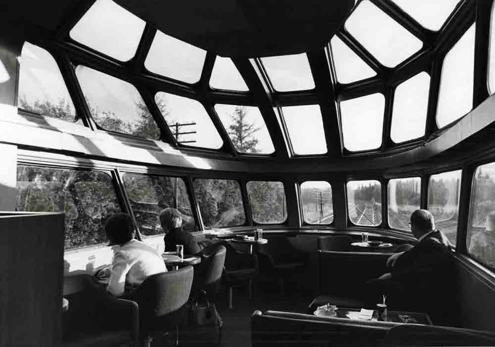 people sitting in an observation car with multiple windows