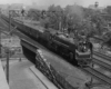 a steam engine passenger train crossing a bridge over a road