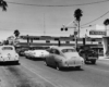 a passenger train crossing a road with cars waiting for it to pas