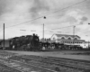a steam engine passenger train by a station