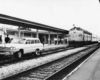 at a passenger station, an automobile is on a set of rails and blocking a passenger train behind it