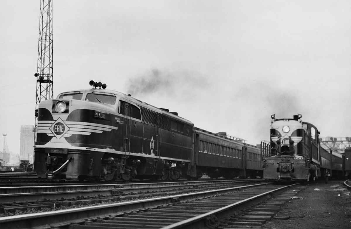 A black and white photo of two trains traveling side by side