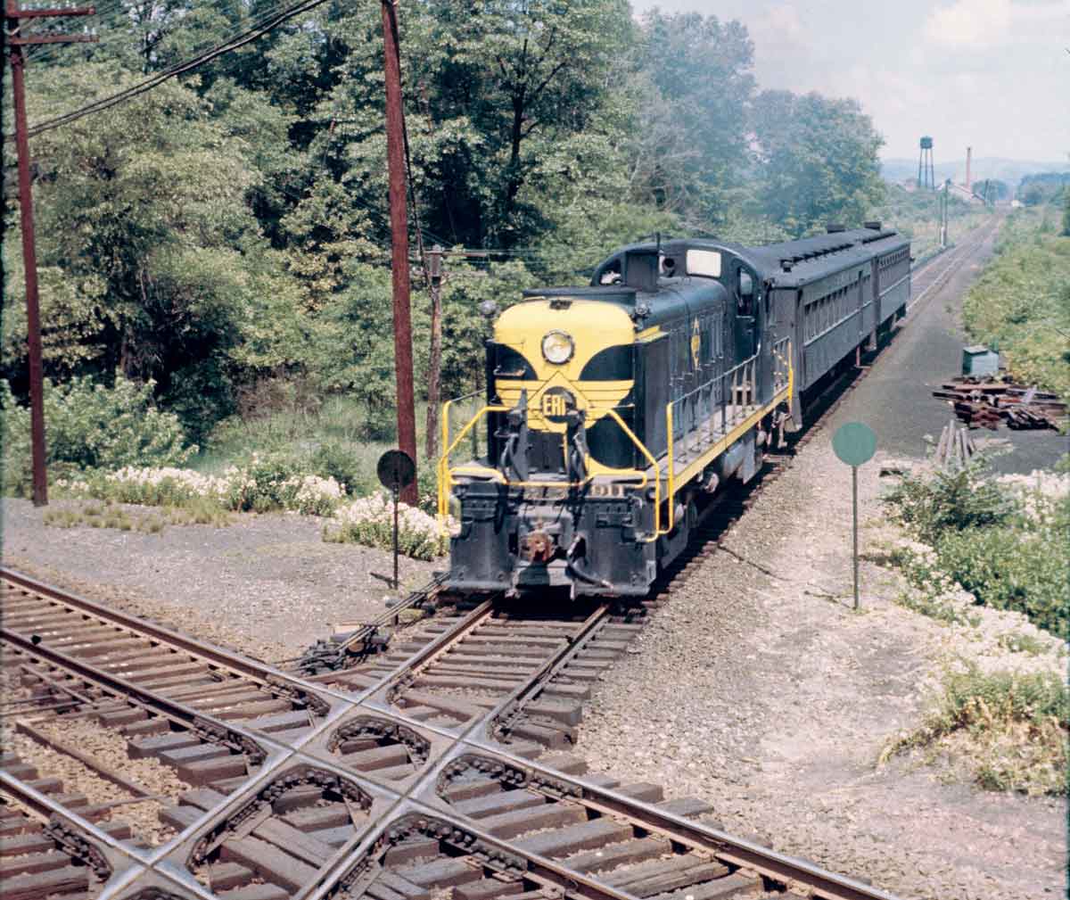 A green and yellow train approaching an intersection