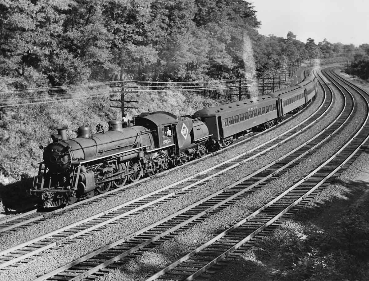 A black and white photo of a train with the conductor out the window