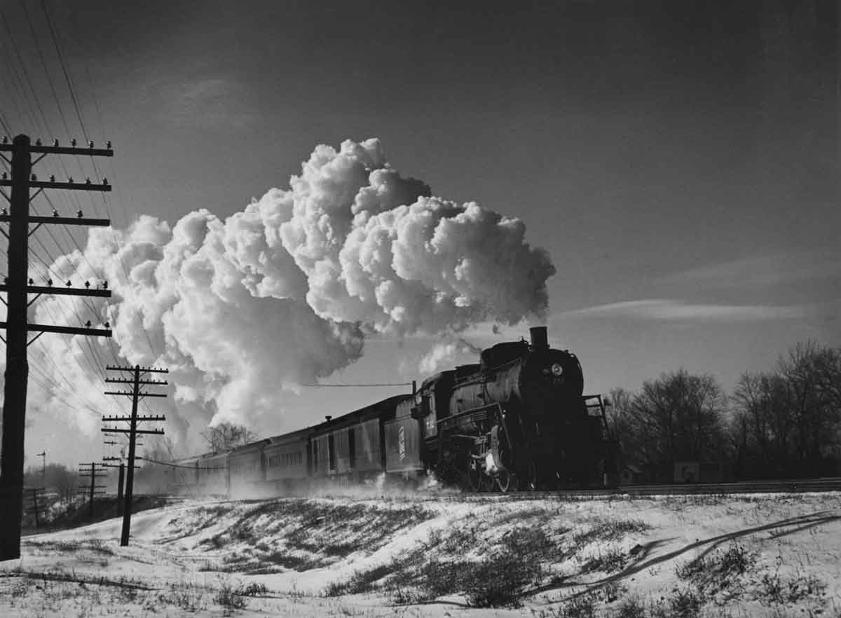 a steam engine with a huge plume of steam on a winter day