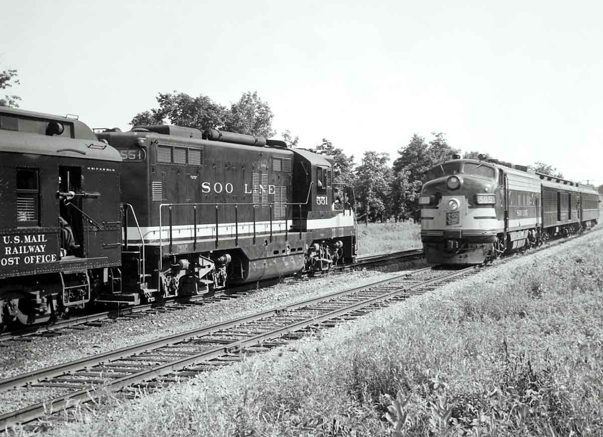 a couple of diesel passenger trains facing each other on two rails