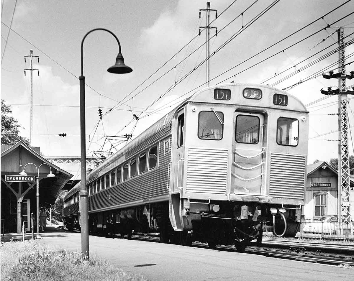 A passenger car parked outside a train station waiting for passengers
