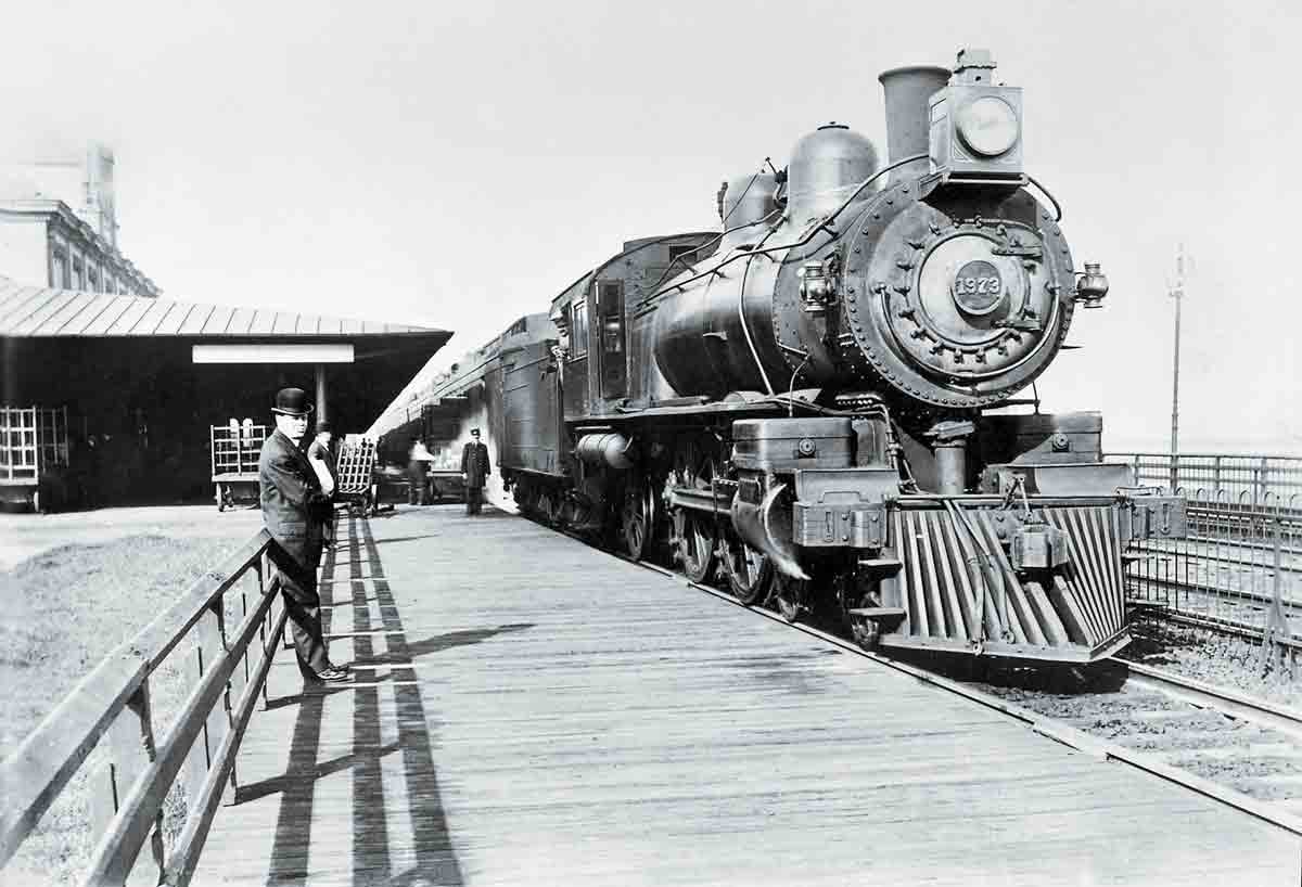 A man leaning against a fence next to a train