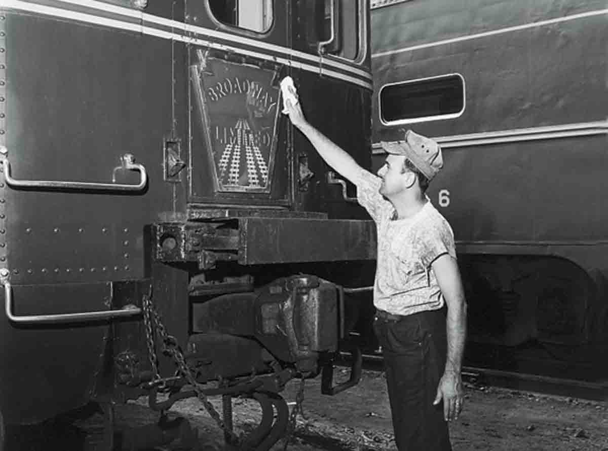 A worker cleaning the back of a train