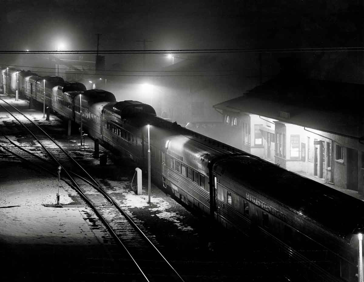 a passenger train sitting at a passenger depot on a snowy night