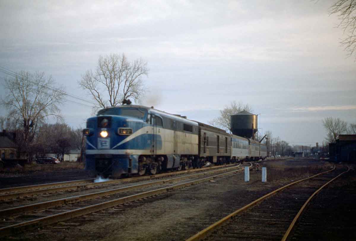 A blue and white train passing by a water tower